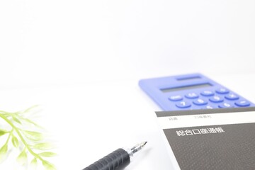 通帳と電卓で資産管理をイメージした白背景の構図
