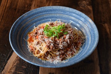 Blue bowl with pasta bolognese garnished with green sprouts