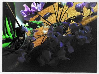 Vibrant purple flowers arranged in a glass vase on a wooden table, with soft natural light...