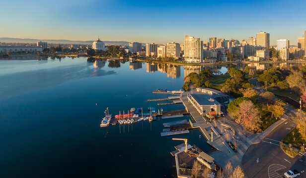 Aerial view of Lake Merritt in Oakland, California, USA, showcasing the city skyline and the calm waters reflecting the buildings during a clear morning.