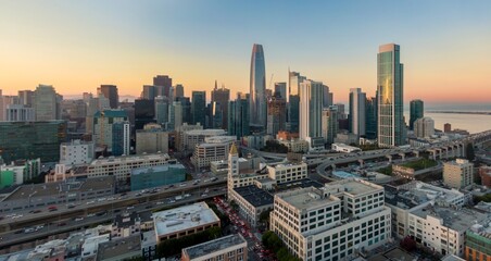 Obraz premium Aerial view of San Francisco, California, USA, at sunset. Cars travel on highways and city streets below the skyline, showcasing urban life and transportation.