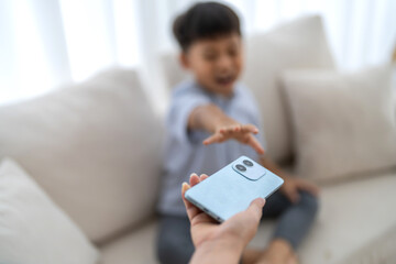 Child reaching for smartphone from parent, screen time control, tech addiction in kids, digital...