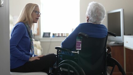 In a cozy indoor space, a daughter visits her elderly mother in a wheelchair, providing care, support, and love during their time together at home.
