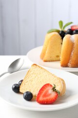 Tasty bundt cake with powdered sugar, berries and mint on white table, closeup