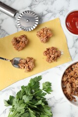 Making ravioli bolognese at white marble table, flat lay