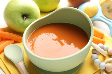 Baby food. Tasty puree in bowl, different ingredients and teether on table, closeup