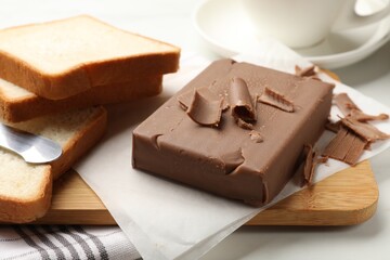 Block of tasty chocolate butter and bread slices on table, closeup