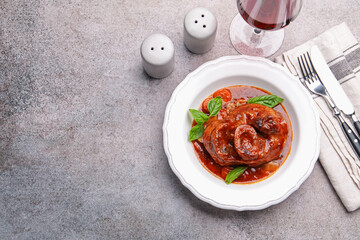 Traditional ossobuco dish with beef steak served on grey table, flat lay. Space for text