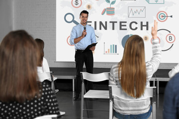 Business trainer giving lecture using video projector in conference room. Fintech word and...