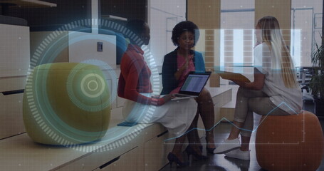 Women in business attire discussing holographic projections in office lounge, sitting on stool