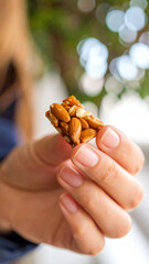 A close-up of a person holding a crunchy snack made with nuts, perfect for nutritious snacking and healthy living.