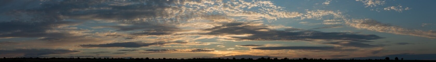 A landscape with an enchanting sunset. Panorama. Tragic gloomy sky. The last flashes of the sun on...