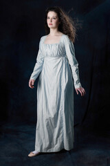 A Regency woman wearing a cotton dress with her long hair blowing in the wind against a studio...