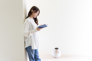 Fototapeta premium 壁にもたれて読書する女性