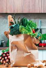 Fresh organic vegetables and baguette in paper bag ready for healthy vegan cooking in the kitchen
