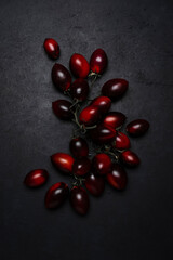 Fresh organic black tomatoes on dark background, ready for healthy food preparation in the kitchen