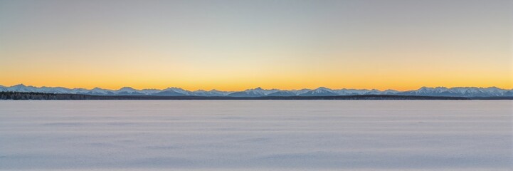 long winter background for banner - Snowy landscape at sunset with distant mountains and clear sky  