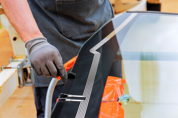 Technician carefully applies adhesive to edge of car windshield during installation windshield at workshop.