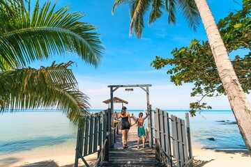 Mother and son on tropical beach with palm trees