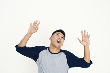 Asian young man is captured raising his hands and expressing surprise