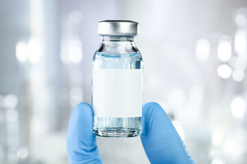 Healthcare concept with a hand in blue medical gloves holding a vaccine vial with blue liquid and black white label