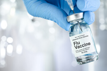 Healthcare concept with a hand in blue medical gloves holding Flu, Influenza, vaccine vial