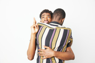 A black man showing affection to his friend, playfully sticking out his tongue. This vibrant moment captures joy and friendship, highlighting cultural connection.