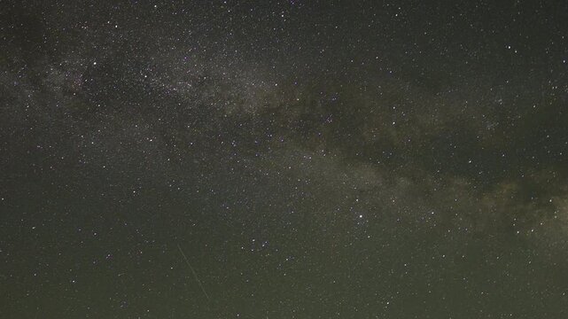 Time lapse of milky way and lot of stars visible on clear night sky and some strikes as satellites and planes pass by while earth rotating changing location of stars creating almost spiral like effect