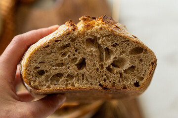 Crispy sourdough bread sits beside a glass jar filled with active starter, accompanied by a rustic...