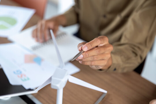 Sustainable Energy Solutions. Close-up of hands designing a wind turbine model for renewable energy.