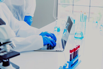 Scientist man using laptop typing computer keyboard in chemical testing science laboratory. Doctor...