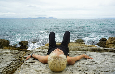 A woman sitting on a rock around Waipu pancake rocks in Waipu, New Zealand.