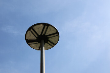 Modern street lamp with circular design against clear blue sky, minimalistic and sleek, emphasizing...