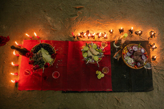 Brazilian Umbanda religious offering to Exu with clay bowl, meat, peppers, onions, candles and alcoholic beverages