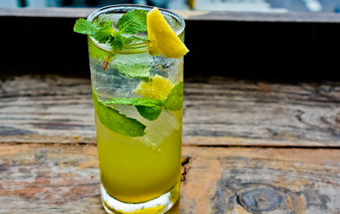view of a glass of lime ice with mint leaves and lemon topping