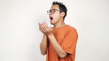 A man in an orange shirt is blowing his nose