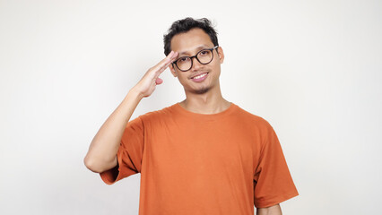 A man in an orange shirt is saluting