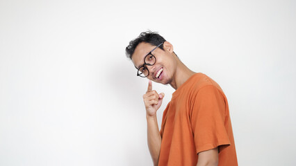 A man in an orange shirt is smiling and pointing to the camera