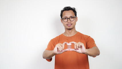 A man in an orange shirt is holding a clear container