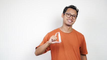 A man in an orange shirt is holding a bottle of medicine and pointing to it