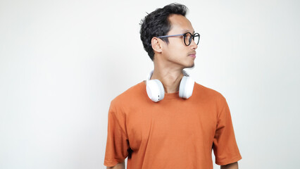 A man wearing glasses and an orange shirt is wearing headphones