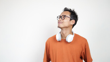A man wearing glasses and an orange shirt is wearing headphones