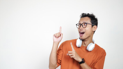 A man in an orange shirt points to the sky with his finger