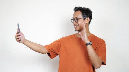 A man in an orange shirt is taking a picture of himself with his cell phone