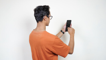 A man in an orange shirt is taking a picture of his phone
