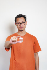 A man in an orange shirt is holding a clear container