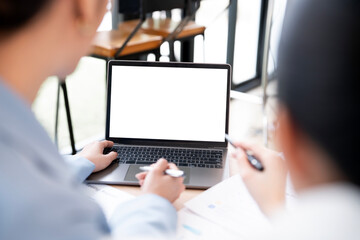 Mockup image of a two woman using laptop with blank screen on wooden table