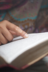 Person reading a quran while pointing to the text