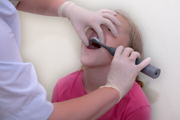 A child is being examined by a dentist in a dentist's office. The dentist is using an electric...