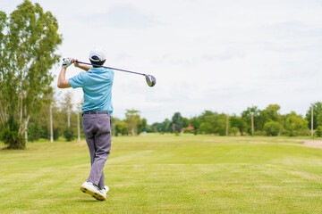 Asian man enjoying the morning round of golf in soft and warm sunlight.